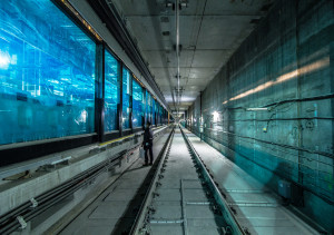 Image of a man standing near metro tracks looking into blue tinted glass.